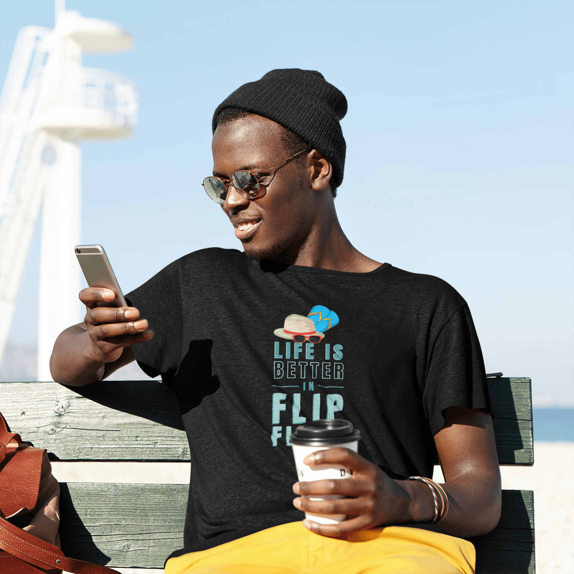 Man wearing black 'Life is Better on Flip Flops' t-shirt outdoors.